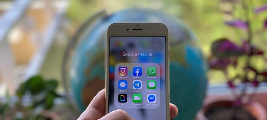 Närbild hand som håller i mobil med olika appar för sociala medier på skärmen