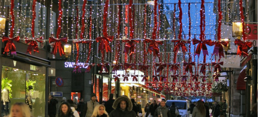 Människor på juldekorerad shoppinggata.