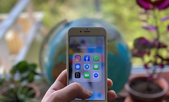 Närbild hand som håller i mobil med olika appar för sociala medier på skärmen